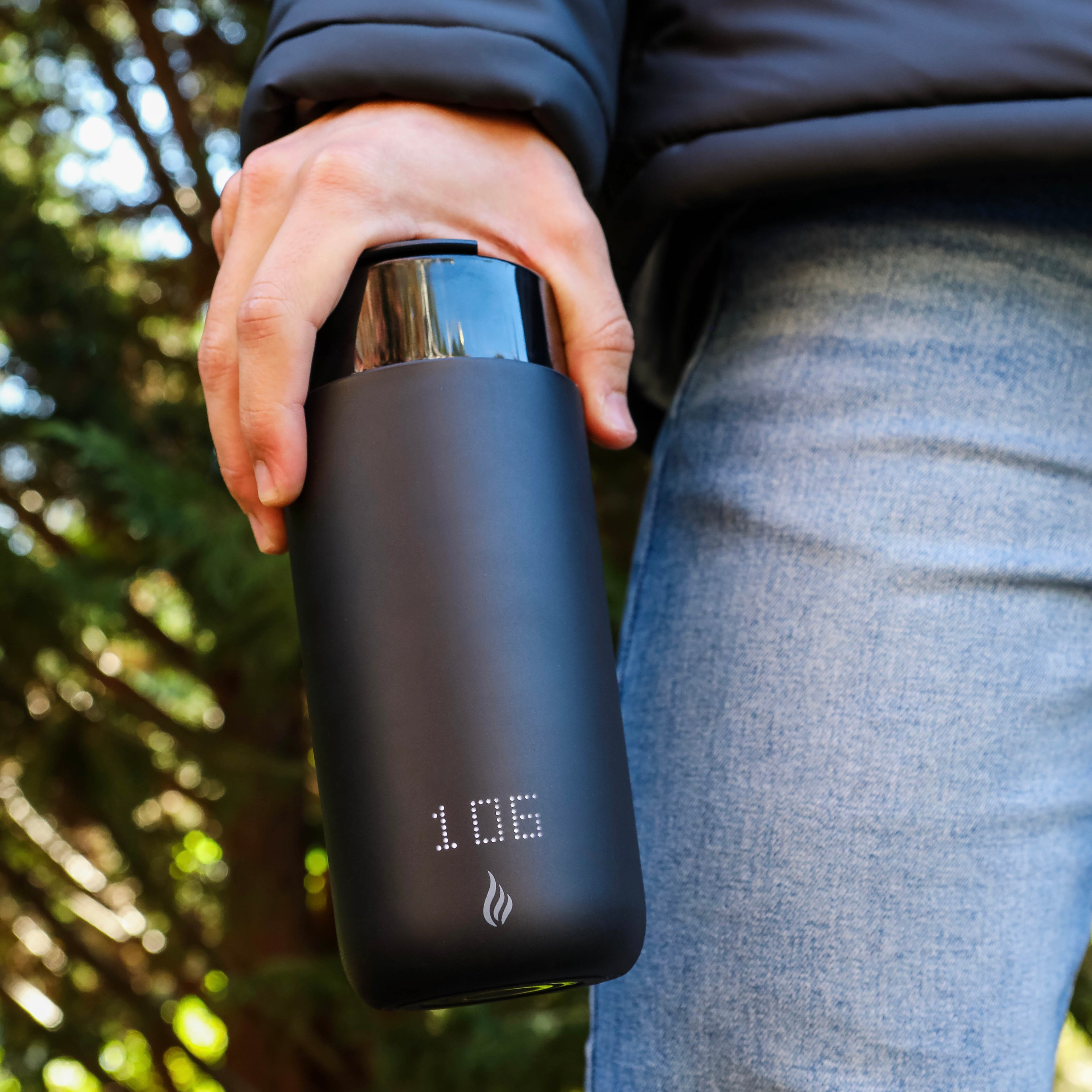 Person holding a black Ciups® GoMug that is heating up their coffee outdoors